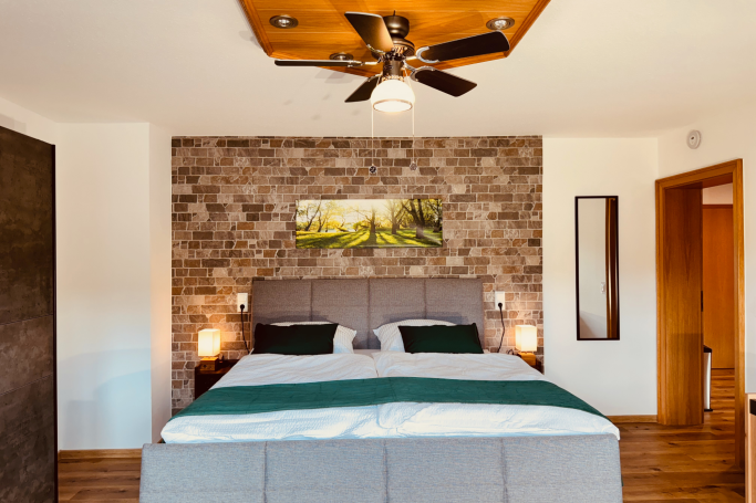 Schlafzimmer im Ferienhaus Taufstein mit komfortablem Boxspringbett und Natursteinwand